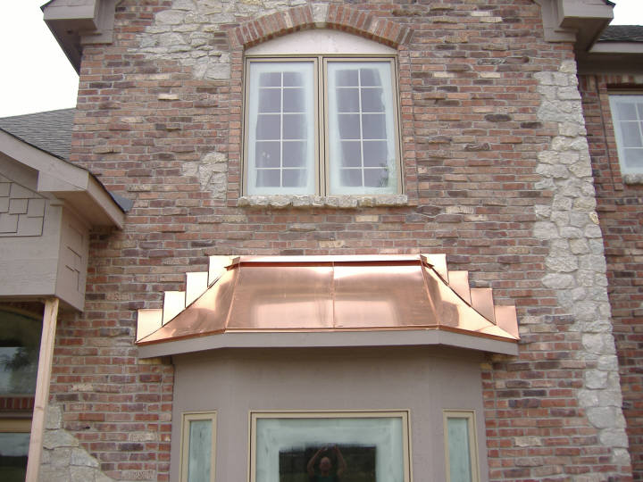 Custom copper standing seam bay window hood roof with stepped copper counter flashing.